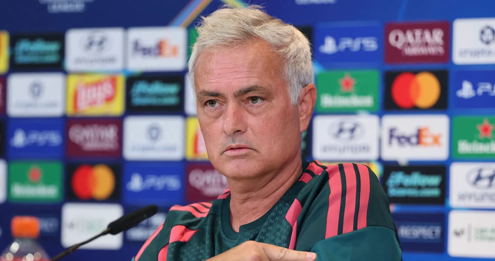 Manager speaking at press conference with logos behind