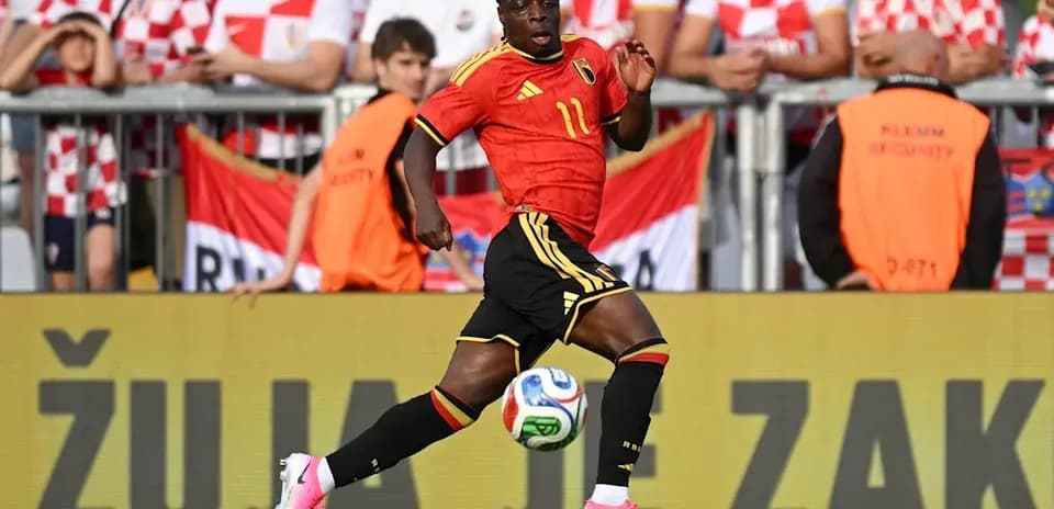 Belgian player dribbling the ball past fans