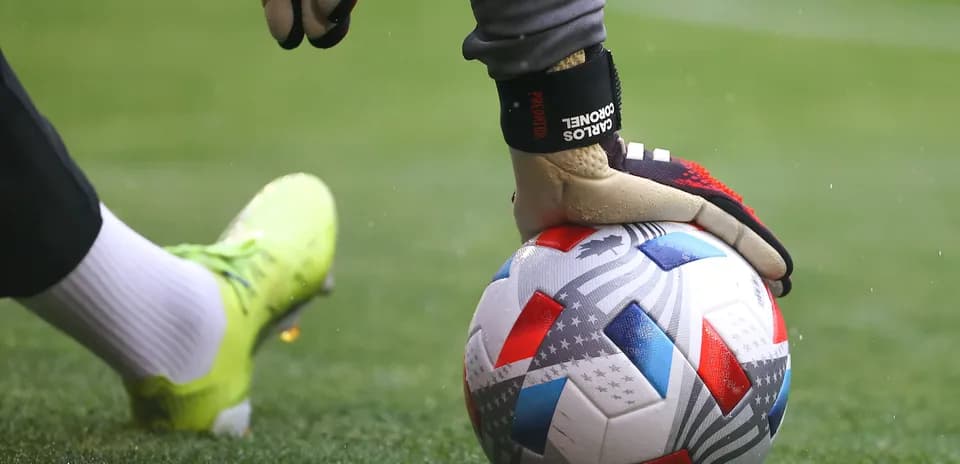 Goalkeeper's hand on soccer ball during play