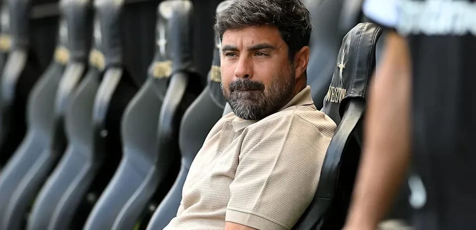 Coach seated on bench during match preparations