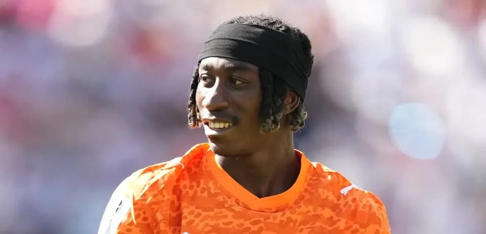 Goalkeeper in orange kit during match warm-up