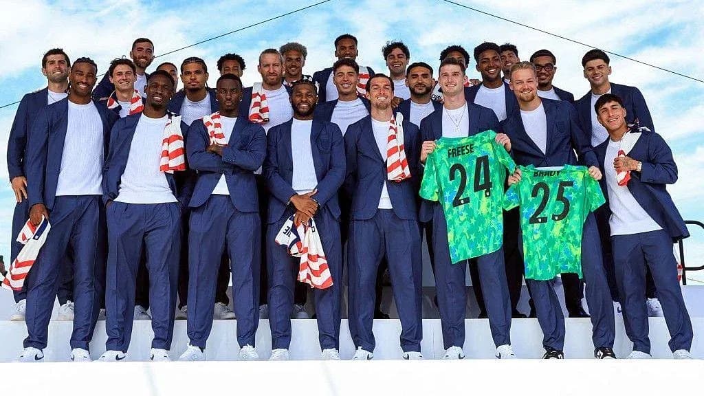 Soccer team posing in suits holding jerseys