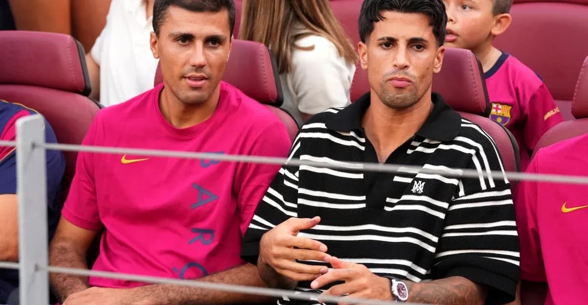 Two men seated in stadium, wearing team jerseys