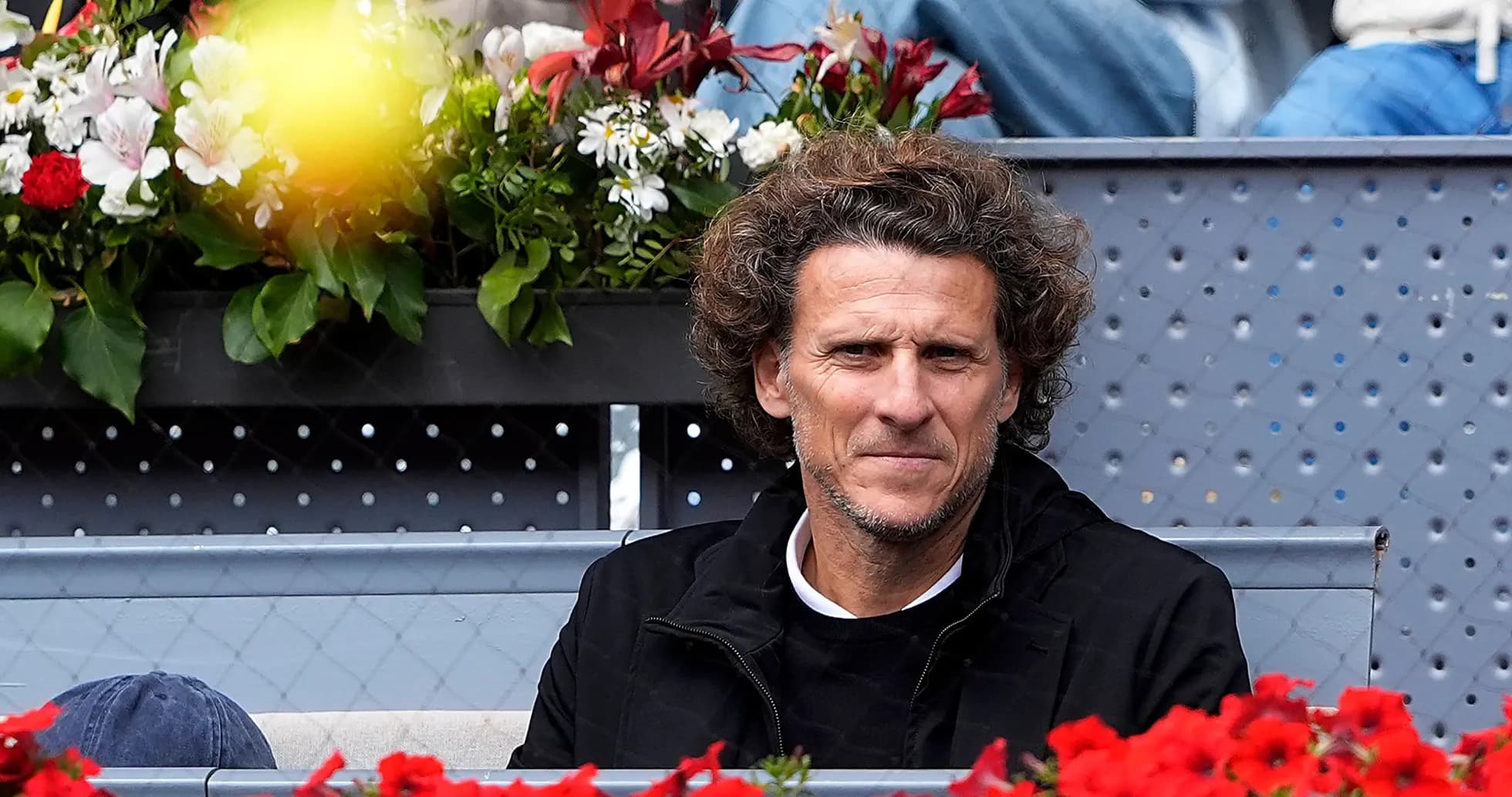 Man sitting in stands with flowers around him
