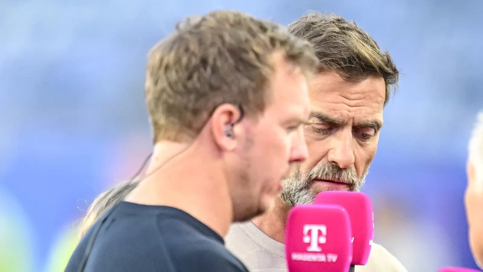 Two commentators speaking into microphones during broadcast