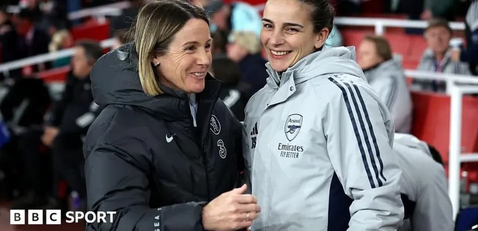 Two coaches smiling and talking on the sidelines