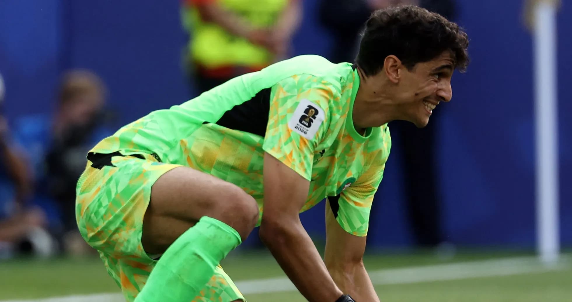 Goalkeeper in bright kit recovering the ball