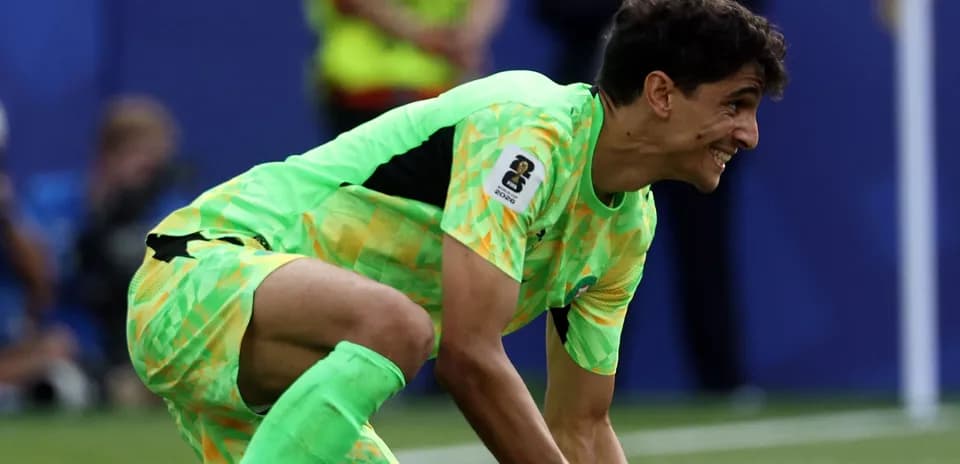 Goalkeeper in bright kit recovering the ball