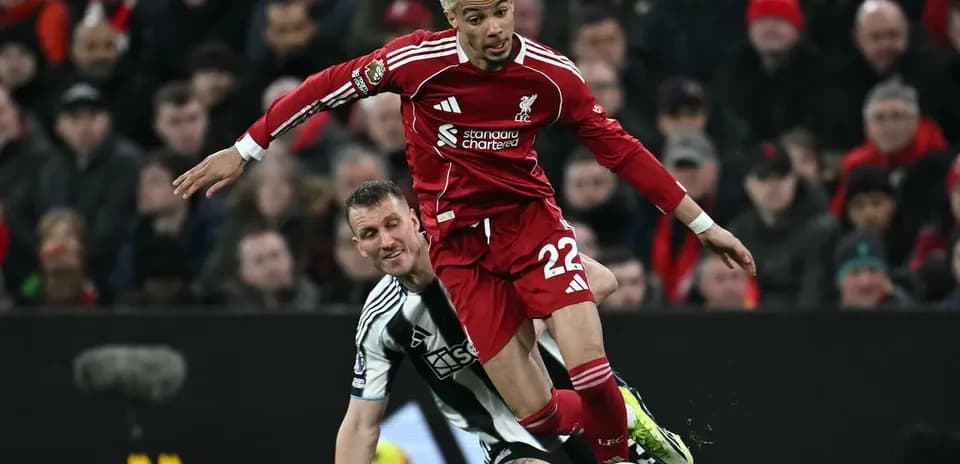 Liverpool player tackling Newcastle opponent during match