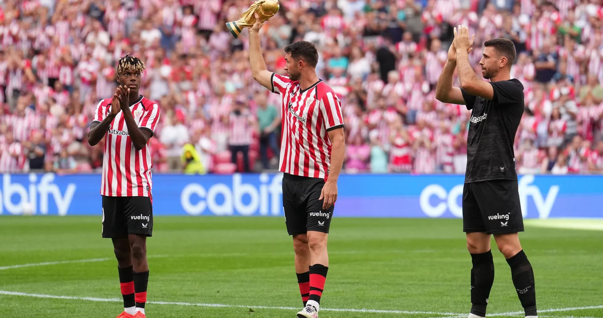 Players celebrating with trophy in front of fans