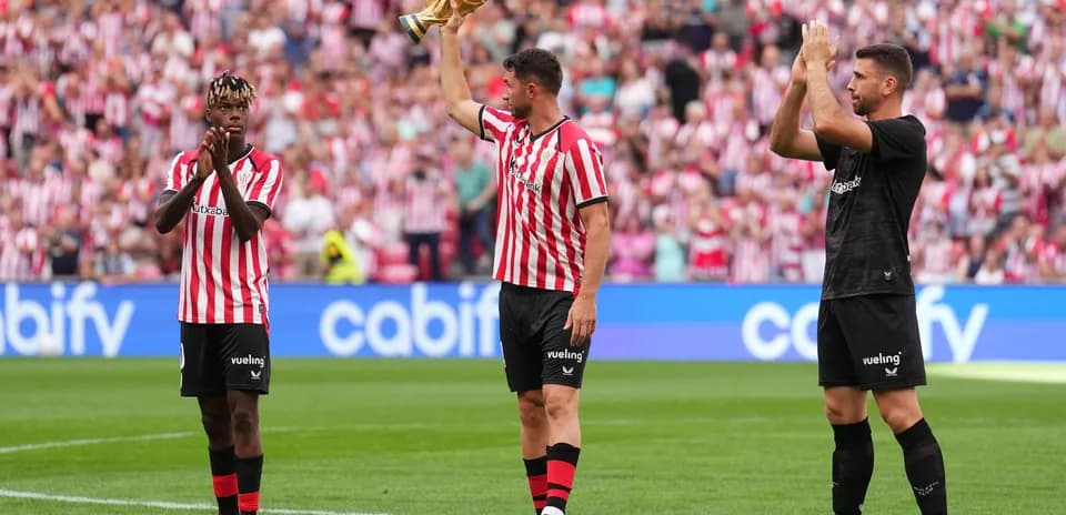Players celebrating with trophy in front of fans