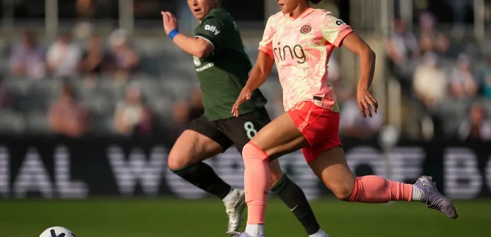 Racing Louisville player dribbling past Portland Thorns opponent