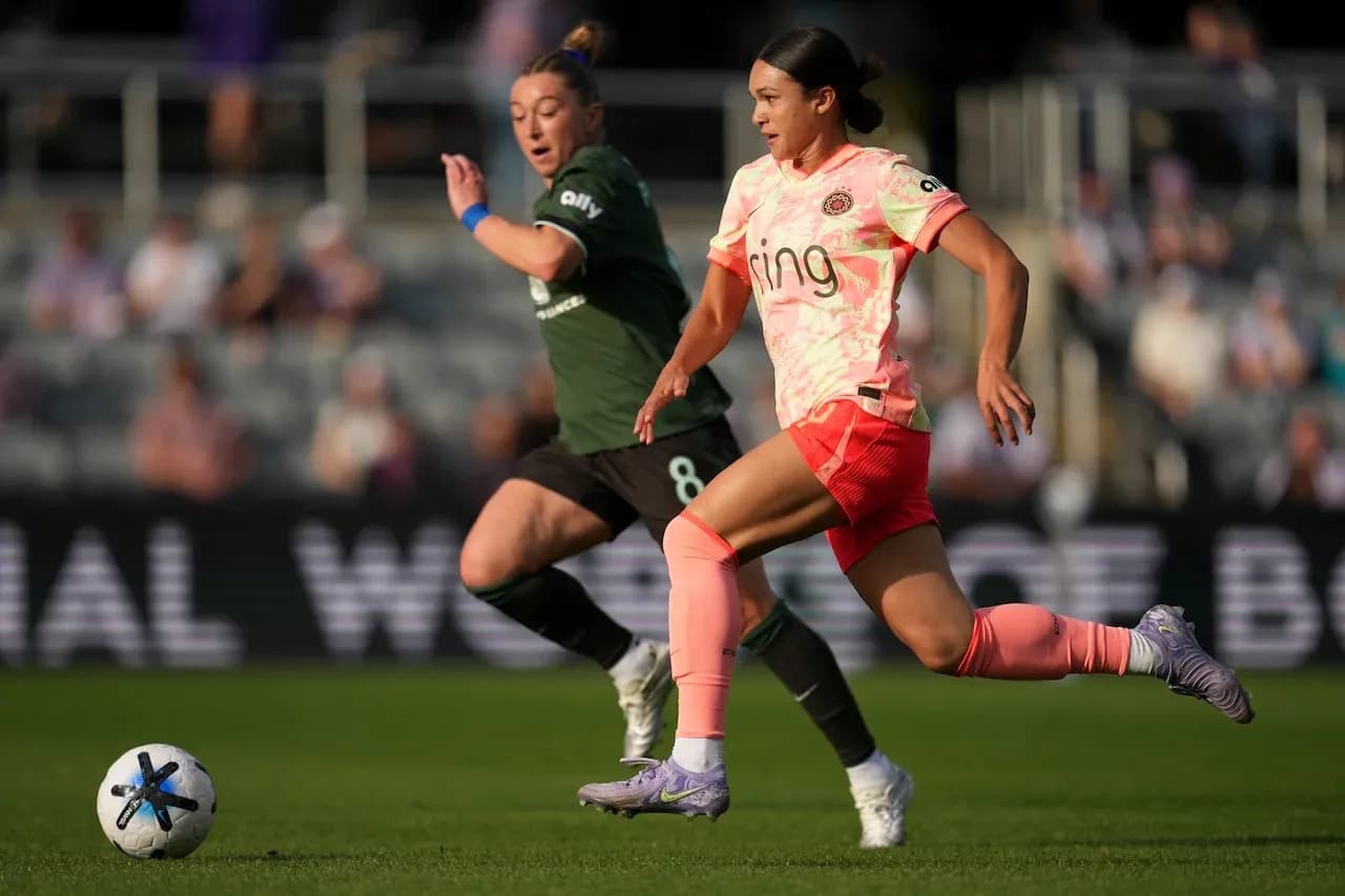 Racing Louisville player dribbling past Portland Thorns opponent