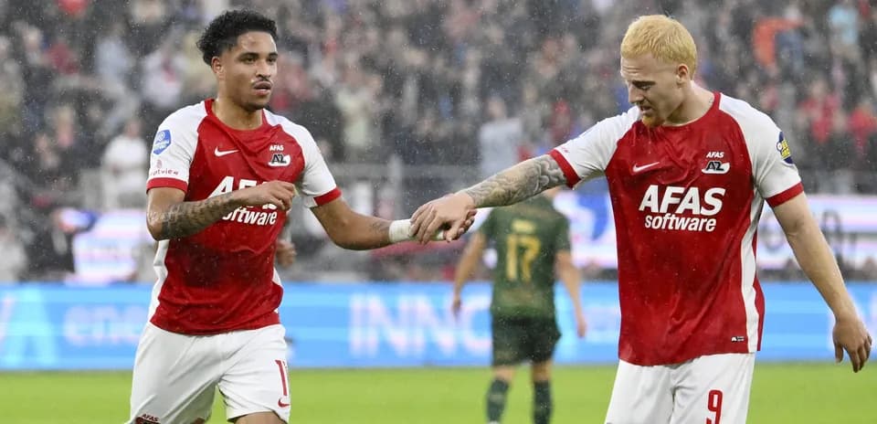 Two AZ Alkmaar players celebrating on rainy pitch