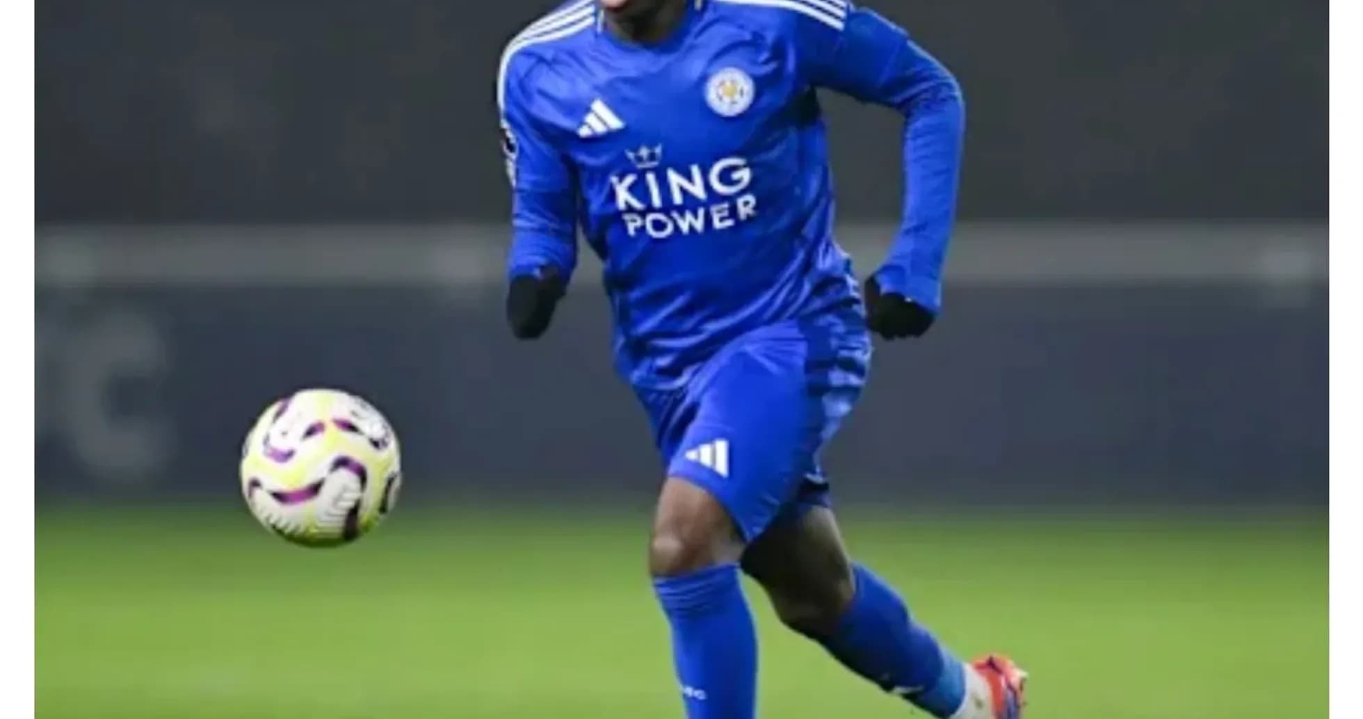 Player in blue kit dribbling ball on field