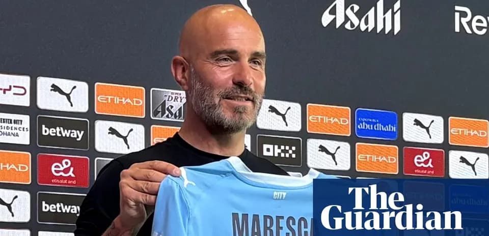 New manager holding Manchester City jersey at press conference
