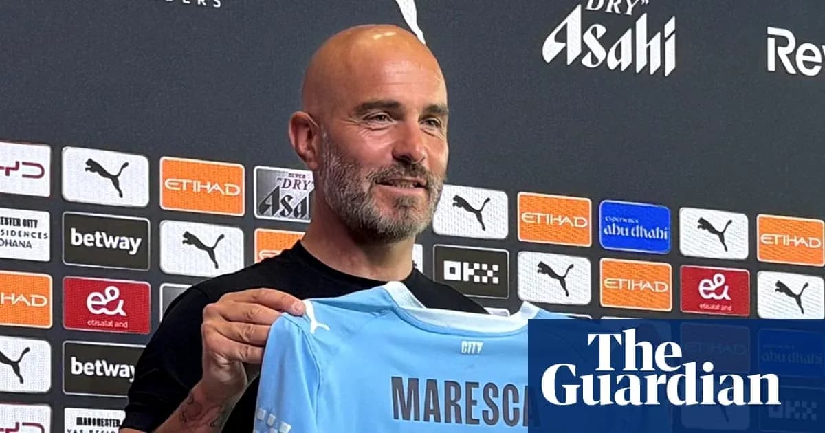 New manager holding Manchester City jersey at press conference