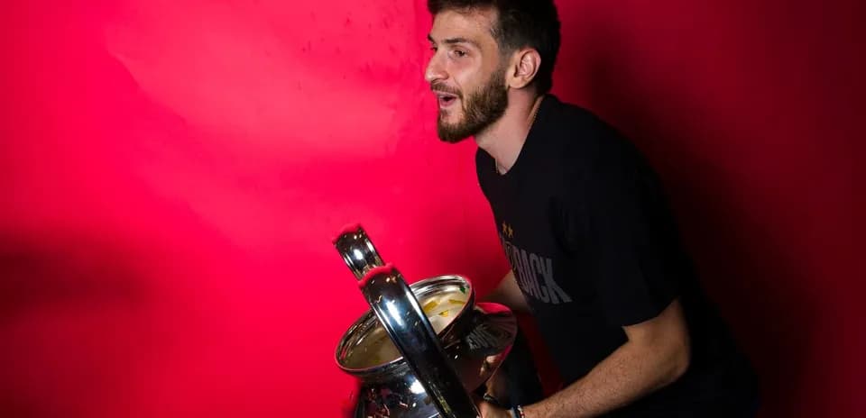 Player celebrating with a trophy against red background