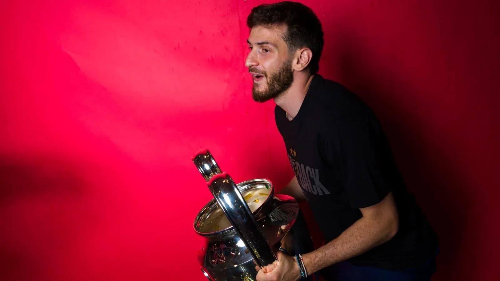 Player celebrating with a trophy against red background