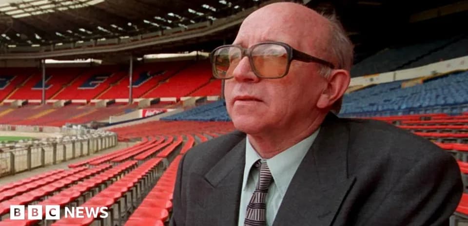 Man seated in empty stadium with red seats
