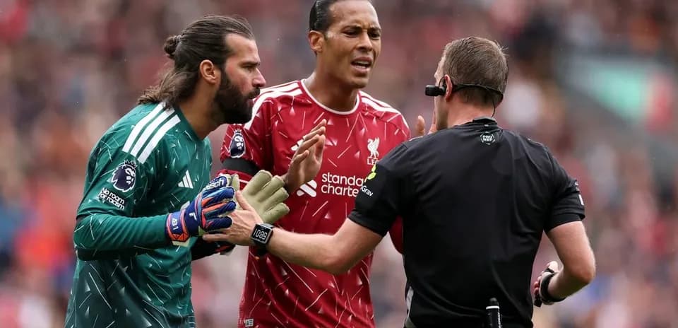 Goalkeeper and defender discussing with referee during match