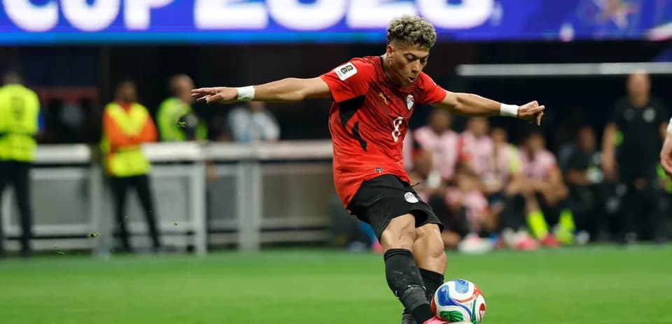 Player in red jersey kicking soccer ball during match