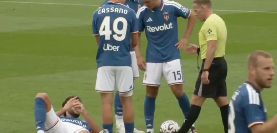 Player lying on field with teammates and referee nearby
