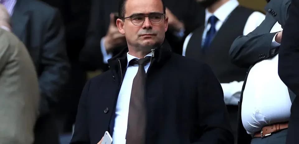 Man in formal attire observing from the stands