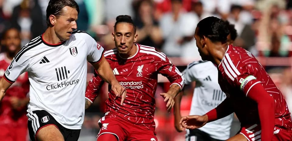Liverpool players challenging Fulham opponent for the ball
