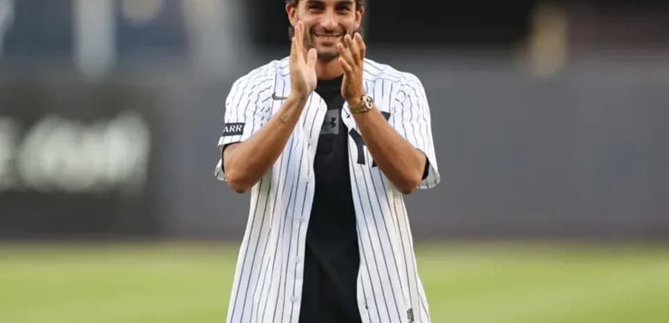 Man in Yankees jersey applauding on baseball field