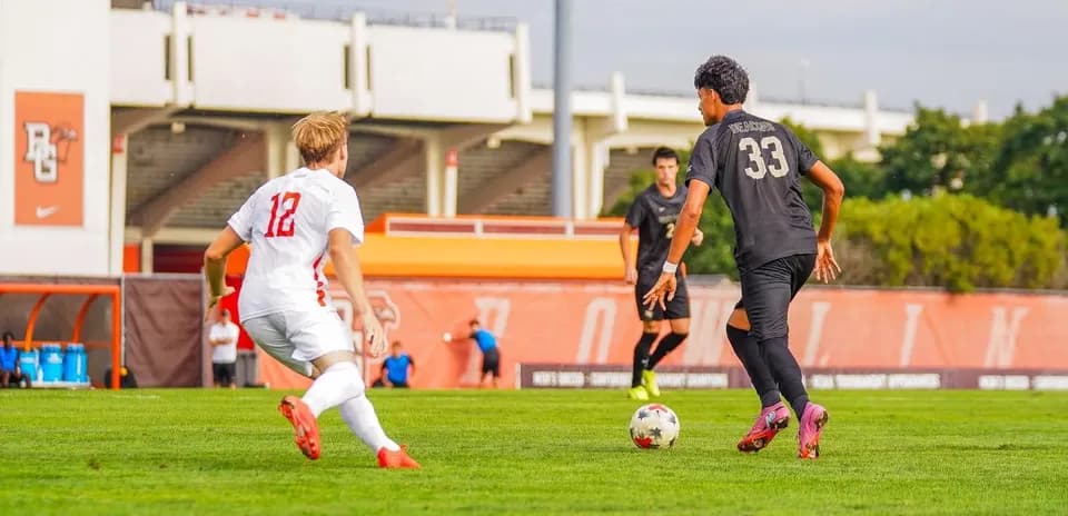 Player in white jersey chasing ball near opponent