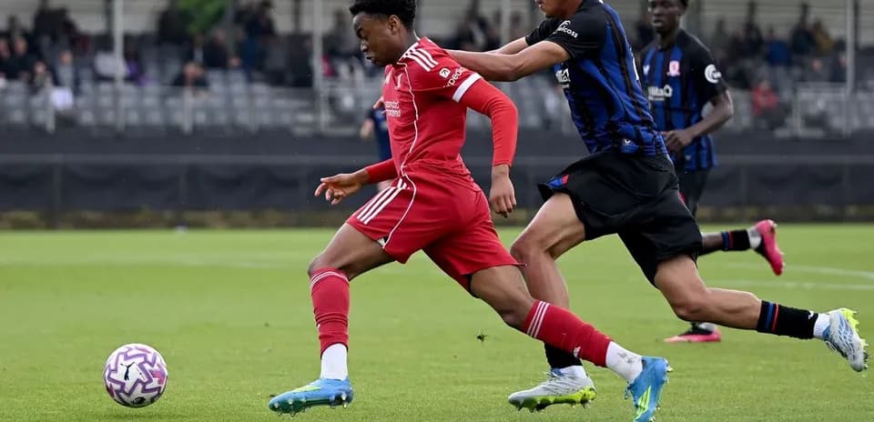 Player in red dribbling past opponent in black