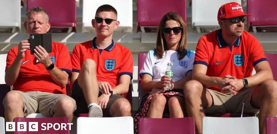 Fans wearing England shirts sitting in stadium