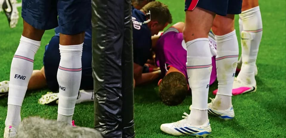 Players gathered around an injured teammate on field