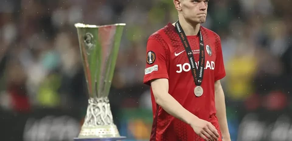 Player in red jersey walking past UEFA trophy