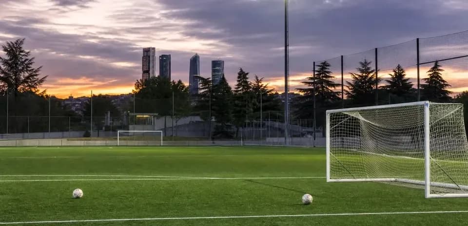 Soccer field with goal and two balls at sunset