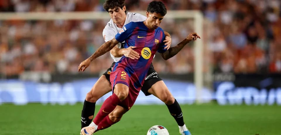 Barcelona player challenged by Valencia opponent during match