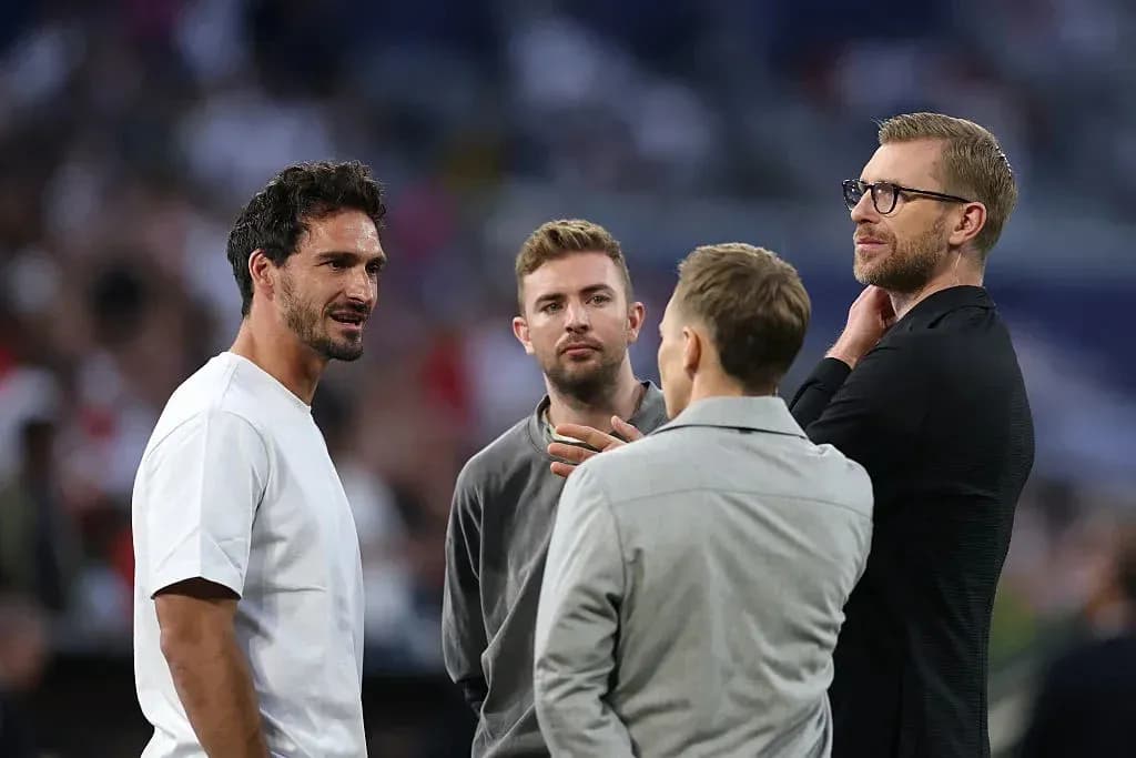 Four men conversing on the sidelines of a match