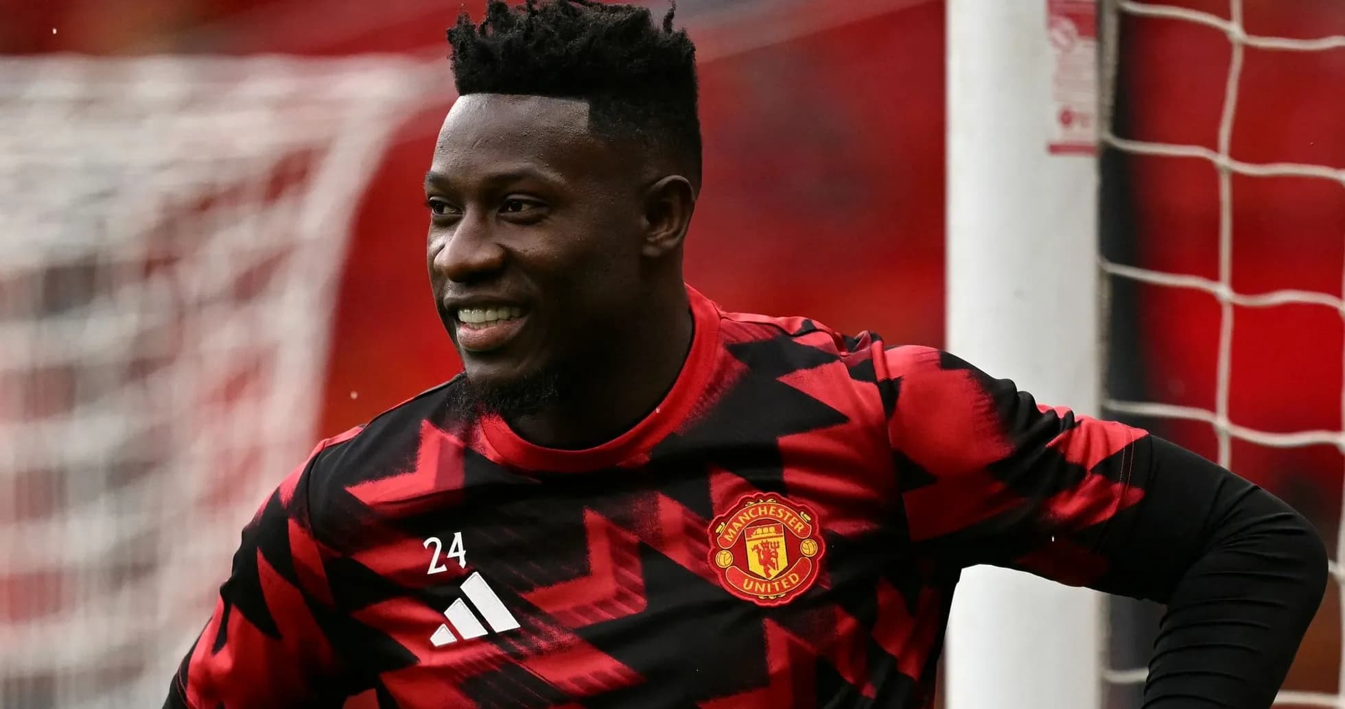 Goalkeeper in Manchester United kit smiling on pitch