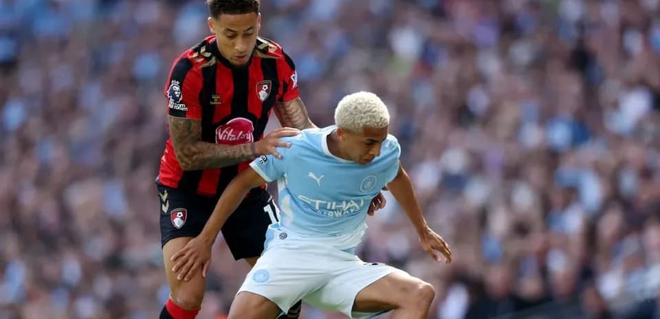 Bournemouth player challenging Manchester City player for ball