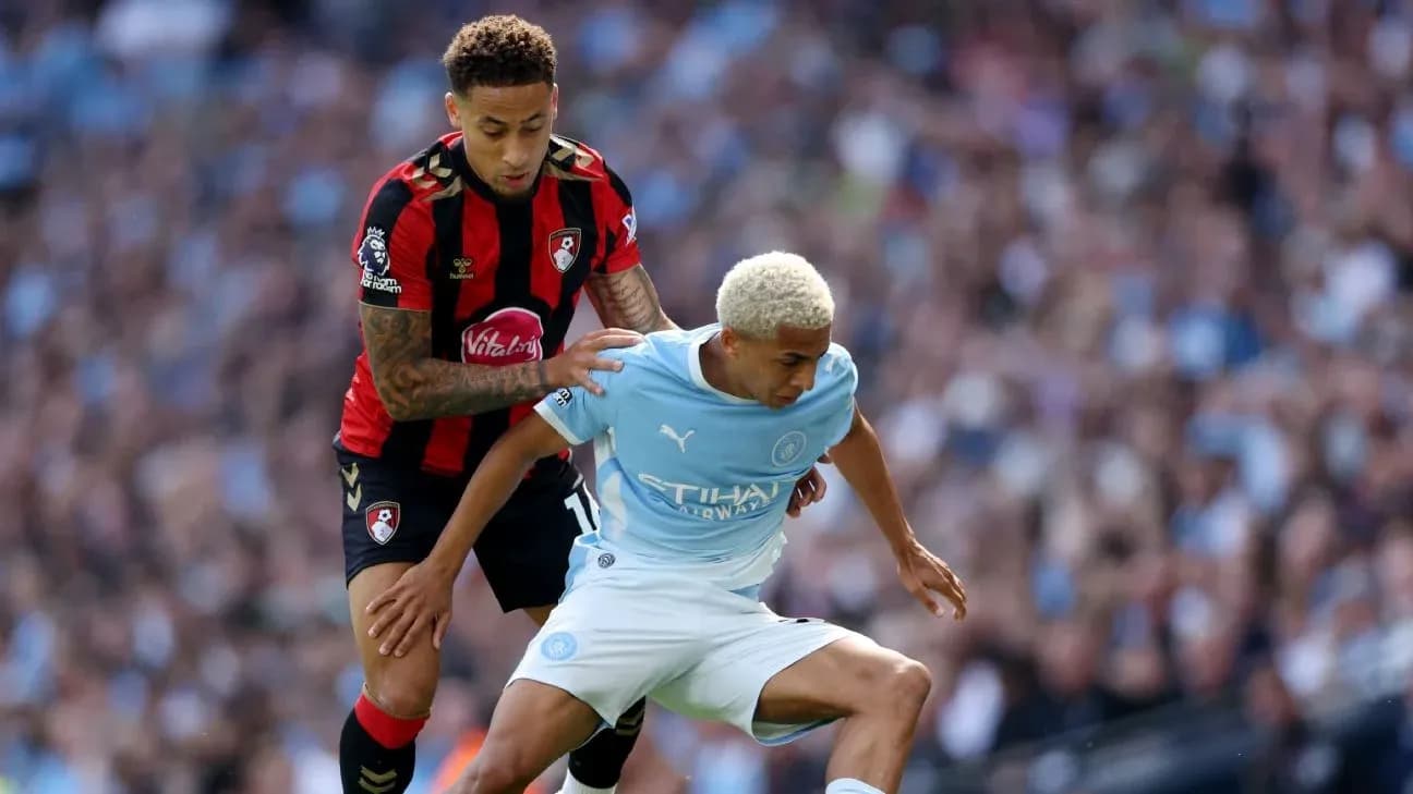 Bournemouth player challenging Manchester City player for ball