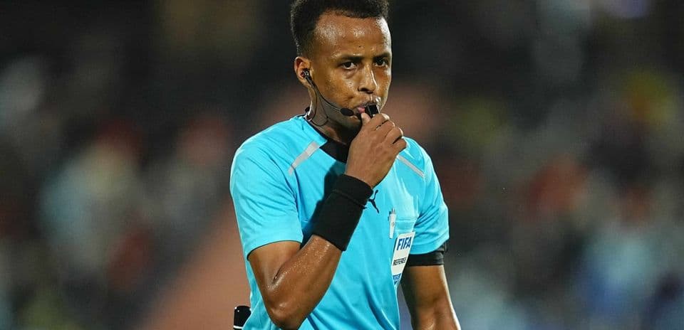 Referee blowing whistle during a football match