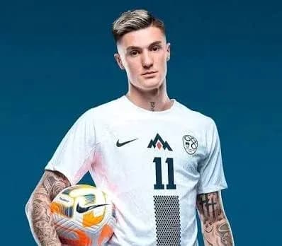 Player posing with a soccer ball in uniform