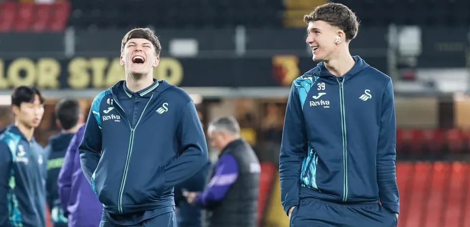 Two Swansea City players smiling during warm-up