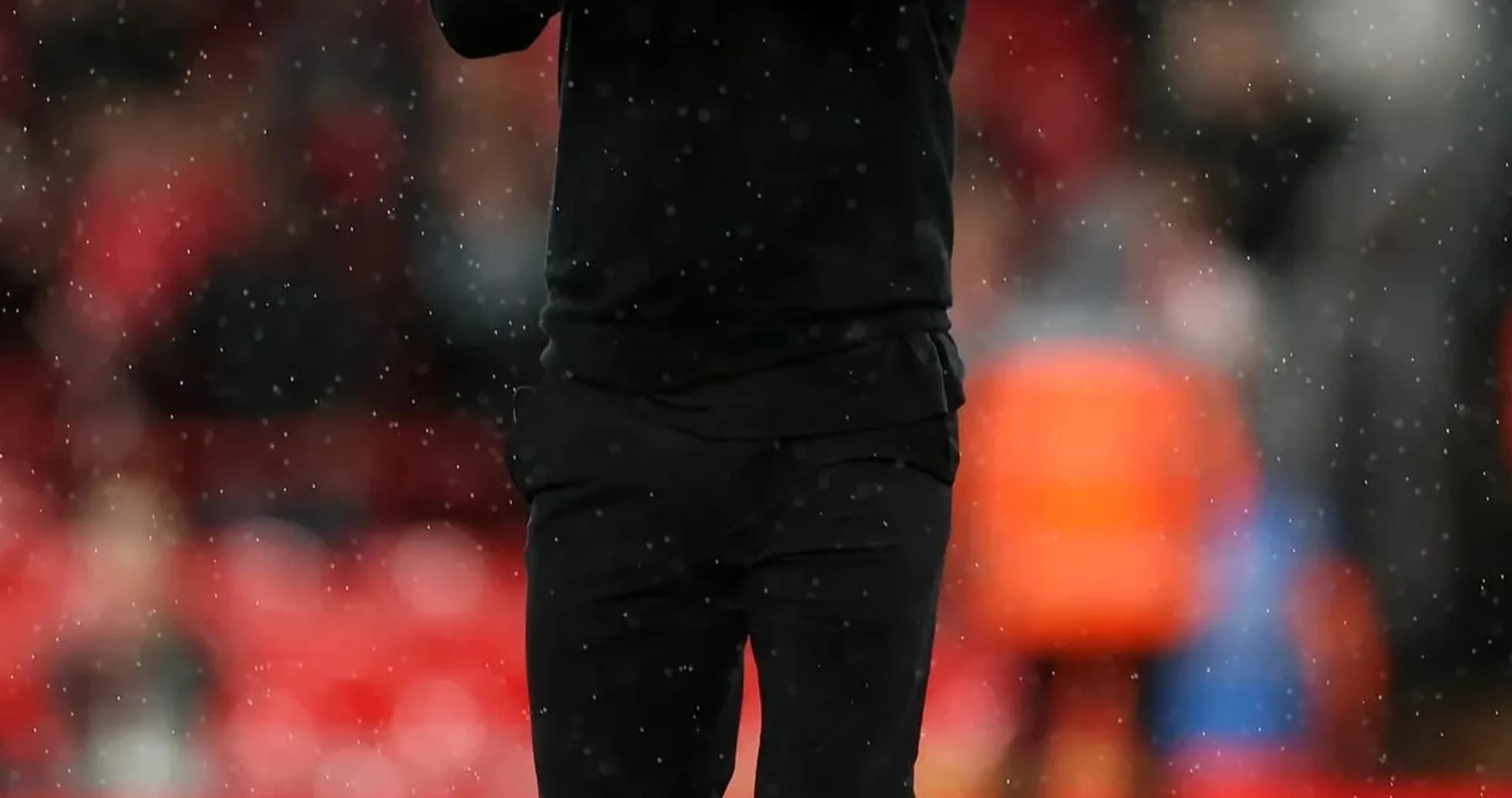 Coach applauding on the pitch during rainy match