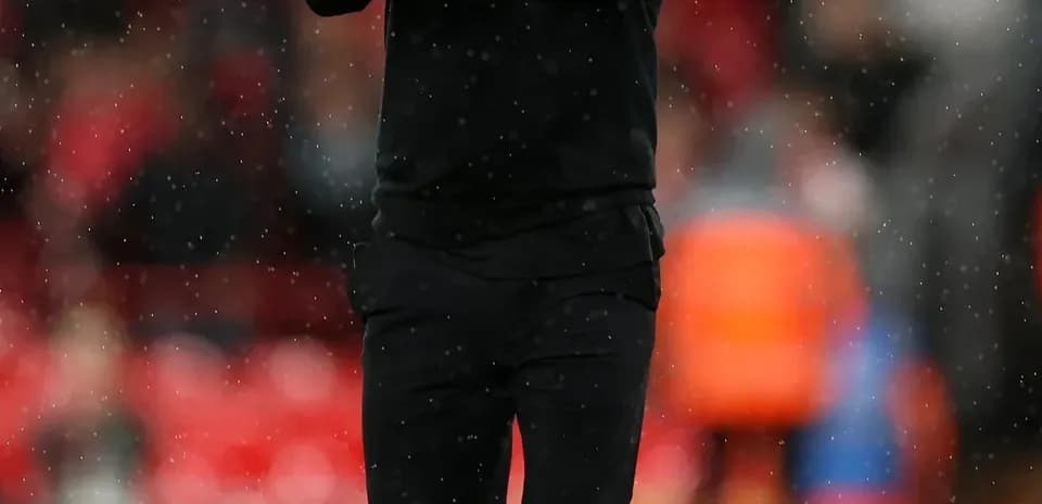 Coach applauding on the pitch during rainy match