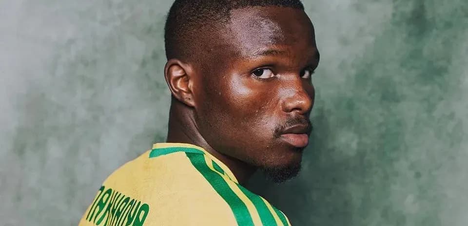 Player posing in yellow jersey with green stripes
