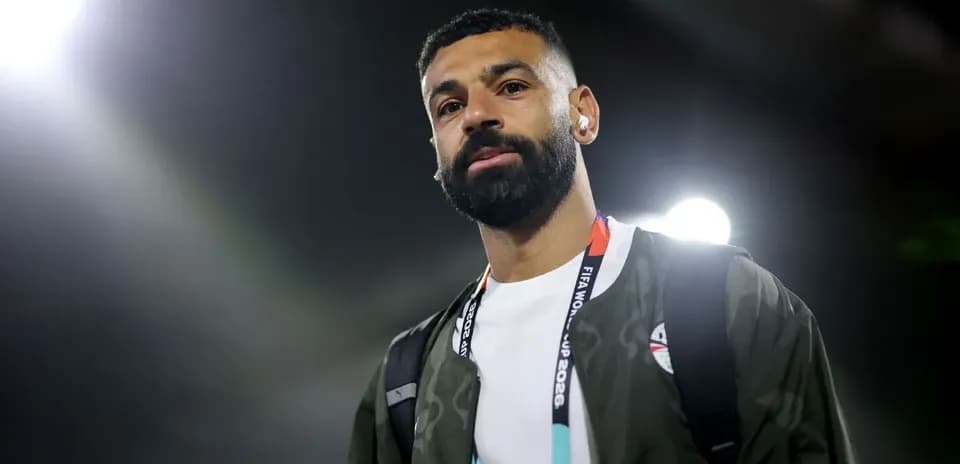 Player walking with headphones and backpack at stadium
