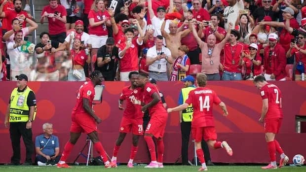 Players celebrating a goal with cheering crowd behind