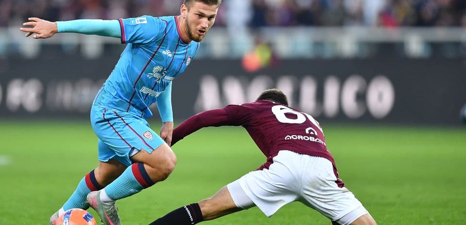 Cagliari player evading a tackle during match